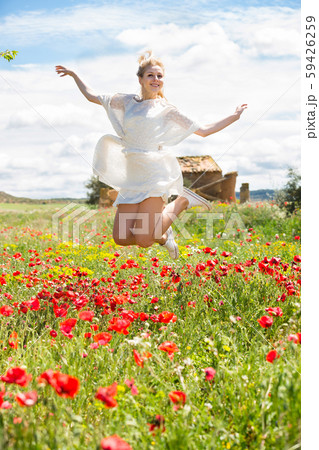 Adult female jumping in poppy field 59426259