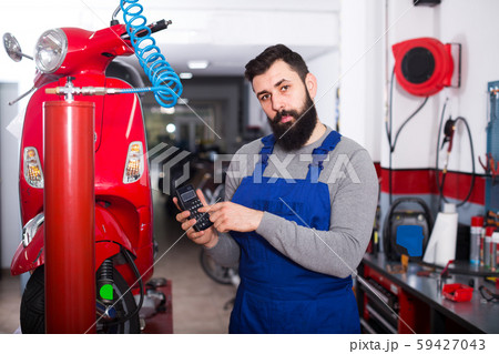 Beardy guy is calculating sum for repairing motorcycle Beardy guy is calculating sum for repairing motorcycle 59427043