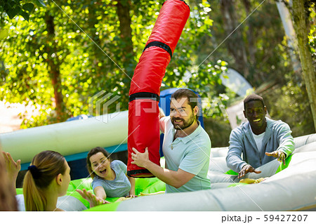 Team of friends playing with inflatable sticks on the trampoline Team of friends playing with inflatable sticks on the trampoline 59427207