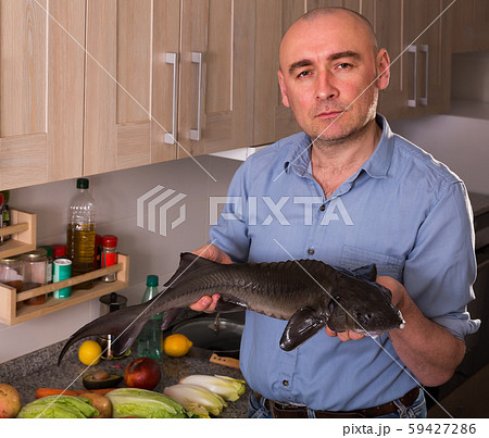 Ordinary man standing holding uncooked sturgeon 59427286