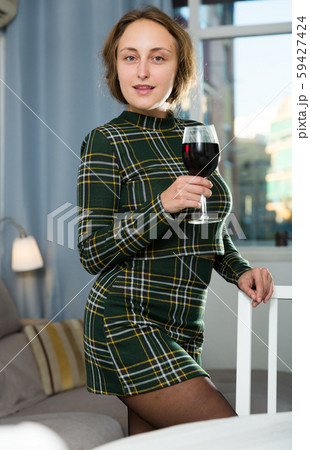Woman standing with wine at home 59427424