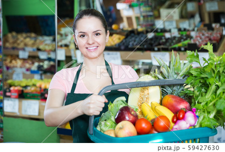smiling woman with range of vegetables and fruits in basket 59427630