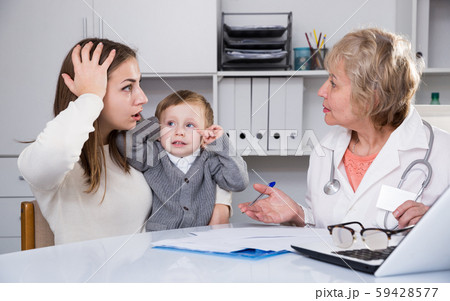Puzzled woman is listening woman doctor about diagnosis her son Puzzled woman is listening woman doctor about diagnosis her son 59428577