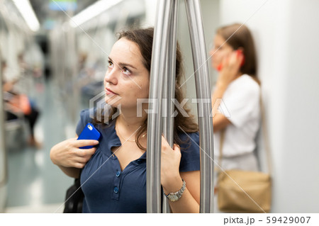 Thoughtful woman traveling by subway car Thoughtful woman traveling by subway car 59429007