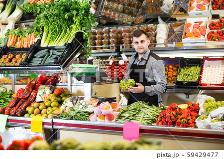Male shop assistant is weighing grapes Male shop assistant is weighing grapes 59429477
