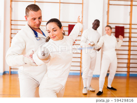 Female practicing movements with trainer at fencing workout 59429816