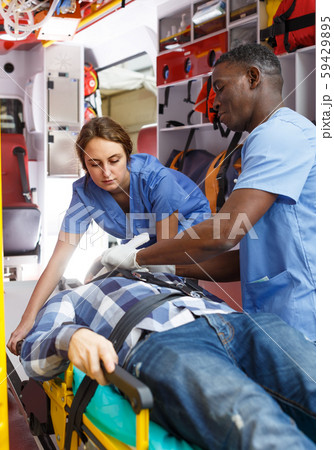 active ambulance team providing medical care to male patient in ambulance car active ambulance team providing medical care to male patient in ambulance car 59429895