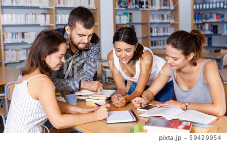 Friendly group of young students studying in university library with female tutor Friendly group of young students studying in university library with female tutor 59429954