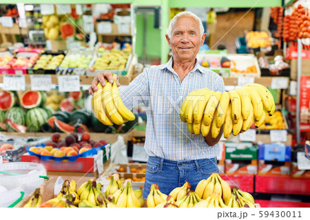 Portrait of smiling older man choosing sweet ripe fruits in farmer market 59430011