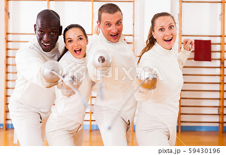 Smiling fencers posing with foils together at fencing room 59430196