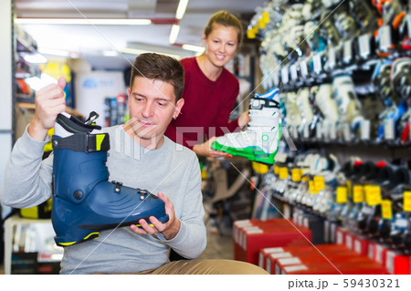 Seller is helping male to trying on ski boots Seller is helping male to trying on ski boots 59430321