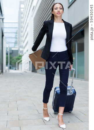Businesswoman in suit with suitcase is going to the hotel 59430545