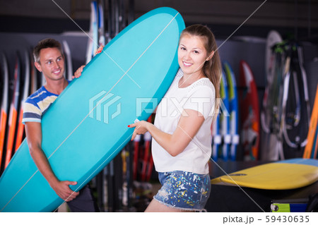 Couple demonstraiting new surfboard 59430635