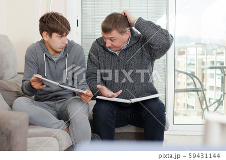 Father and teen son solve school assignment together 59431144