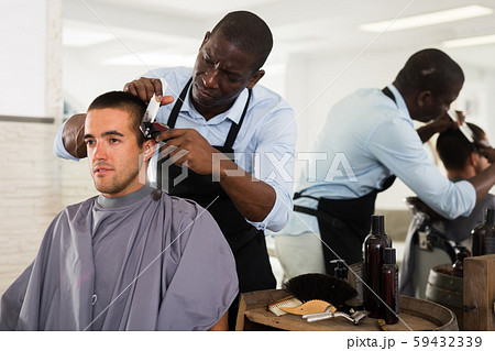 Man getting haircutting by African barber 59432339