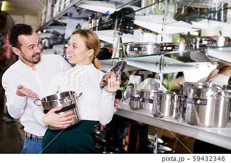 Couple examining various saucepans in dinnerware store Couple examining various saucepans in dinnerware store 59432346