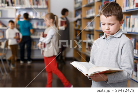 Upset tween boy browsing book 59432478