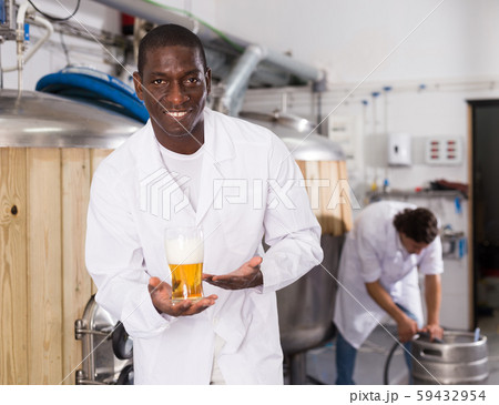 African american man brewer is standing with glass of beer African american man brewer is standing with glass of beer 59432954