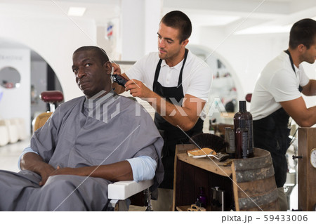 Stylist performing haircut of African man 59433006