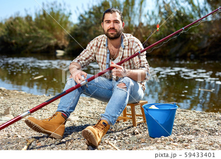 Adult male fisherman pulls fishing line on a fishing rod 59433401