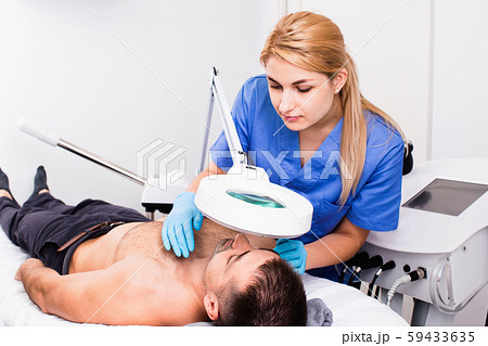 Confident woman cosmetologist examining male client face before procedure in esthetic clinic Confident woman cosmetologist examining male client face before procedure in esthetic clinic 59433635
