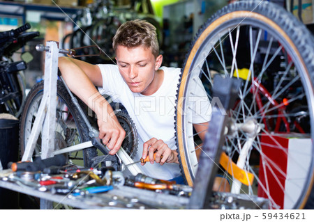 Man repairing bicycles with instruments indoors Man repairing bicycles with instruments indoors 59434621