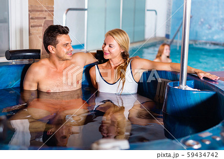 Portrait of couple who is resting in pool in spa salon. 59434742