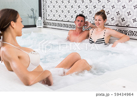 Smiling friends enjoying in jacuzzi 59434964
