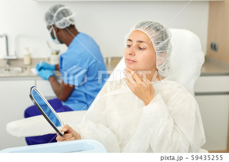 Female client looking to mirror before mesotherapy in esthetic cosmetology clinic 59435255