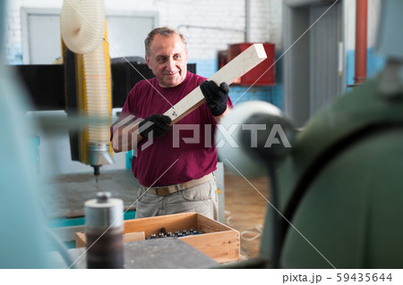 Concentrated worker is shaping timber on woodworking machine at the factory Concentrated worker is shaping timber on woodworking machine at the factory 59435644