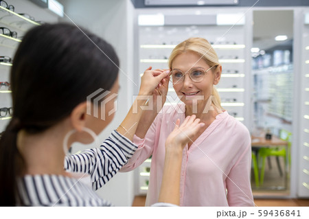 Gorgeous woman trying to choose ideal shape of glasses frame 59436841