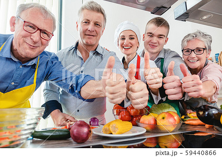 Trainees and their nutritionist in a training kitchen showing thumbs Trainees and their nutritionist in a training kitchen showing thumbs 59440866