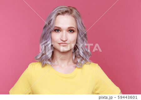 Portrait of young woman in yellow colored T-shurt standing isolated over the pink background. 59443601