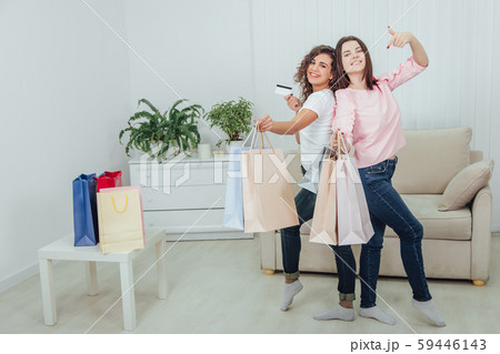 Happy girls are at home after shopping. They are smiling, standing shoulder to shoulder with a lot Happy girls are at home after shopping. They are smiling, standing shoulder to shoulder with a lot 59446143