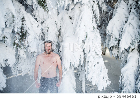 Topless young man outdoors in snow in winter forest, having fun. Topless young man outdoors in snow in winter forest, having fun. 59446461