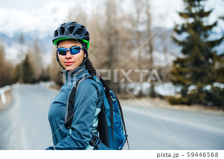 Female mountain biker standing on road outdoors in winter nature. Female mountain biker standing on road outdoors in winter nature. 59446568