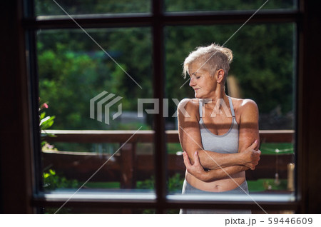 A senior woman with sports bra standing outdoors on a terrace in summer. A senior woman with sports bra standing outdoors on a terrace in summer. 59446609
