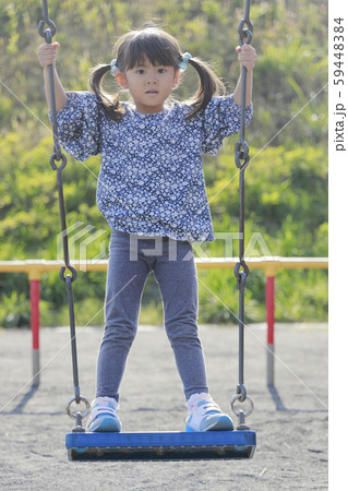 ブランコで立ちこぎをする幼児 5歳児 の写真素材