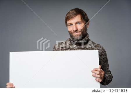 Smiling mature man in warm sweater holding white banner Smiling mature man in warm sweater holding white banner 59454633