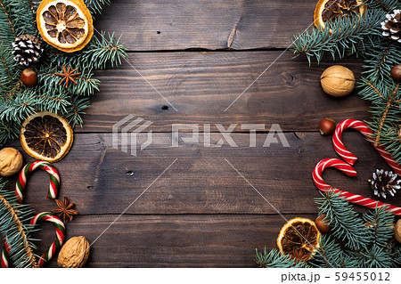 Frame of Christmas tree cones oranges caramel cane nuts on dark wooden background. Copy space. Flat lay. 59455012