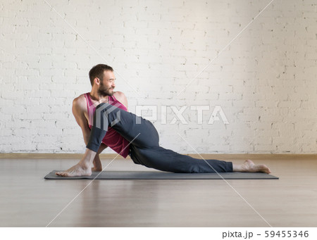 Caucasian fit man doing warm-up stretching on grey mat in fitness studio, twisted pose, selective Caucasian fit man doing warm-up stretching on grey mat in fitness studio, twisted pose, selective 59455346