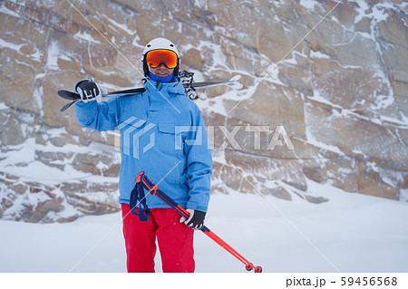 Photo of happy sportsman in helmet with skis in hand on background of mountain in winter Photo of happy sportsman in helmet with skis in hand on background of mountain in winter 59456568