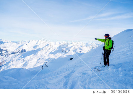 Athletic man pointing hand away while skiing on snowy slope. Athletic man pointing hand away while skiing on snowy slope. 59456638