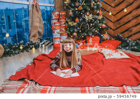 Happy child in knitted reindeer sweater, sealing envelope to Santa with Christmas presents wish list Happy child in knitted reindeer sweater, sealing envelope to Santa with Christmas presents wish list 59456749