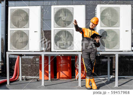 Workman servicing air conditioning or heat pump with digital tablet 59457968