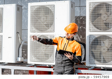 Workman servicing air conditioning or heat pump with digital tablet 59457969