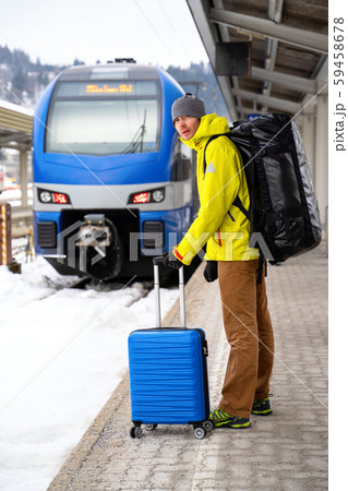 Tourist looking at camera with blue suitcase at station waiting for train Tourist looking at camera with blue suitcase at station waiting for train 59458678