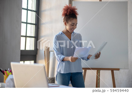 Designer standing near drawing easel and looking at sketches 59459440