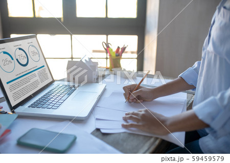 Designer drawing sketches and reading news on laptop Designer drawing sketches and reading news on laptop 59459579