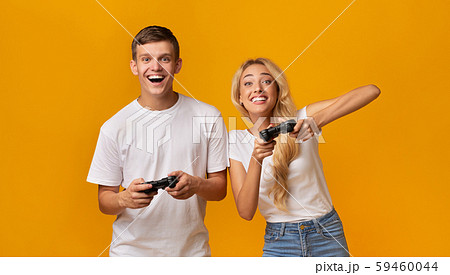 Cheerful couple playing video game with joysticks, having fun together Cheerful couple playing video game with joysticks, having fun together 59460044